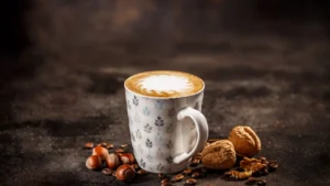 Freddo latte σε ποτήρι με αφρό, τοποθετημένο μπροστά από το λογότυπο του Καφεκοπτείου Καφέ Ναι.