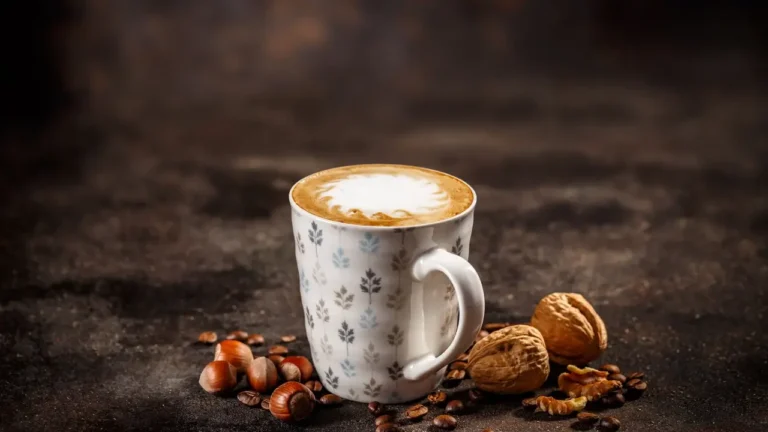 Freddo latte σε ποτήρι με αφρό, τοποθετημένο μπροστά από το λογότυπο του Καφεκοπτείου Καφέ Ναι.